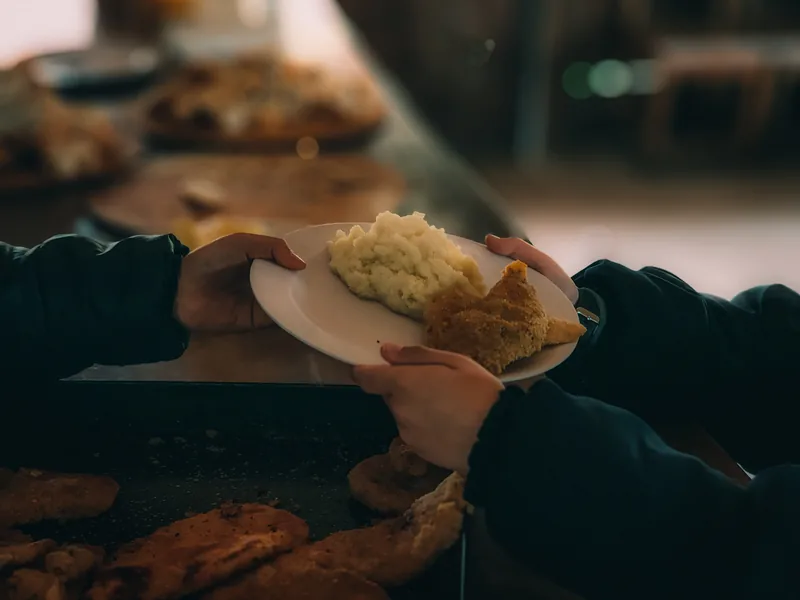 Un plato de milanesa con puré servido en la barra del quincho