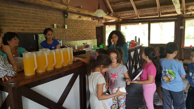 Chicos haciendo fila en la barra del quincho, con las jarras de jugo listas