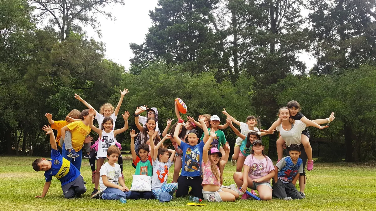 Un grupo de chicos festejando en el parque de BioHuellas, con los brazos en alto