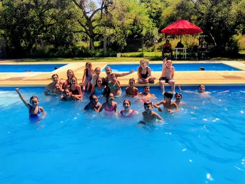 Un grupo de lobatos saluda con los brazos en alto desde la pileta