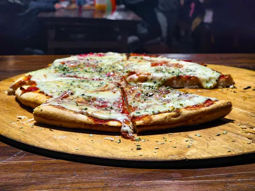 Pizza casera cortada en porciones sobre una tabla de madera
