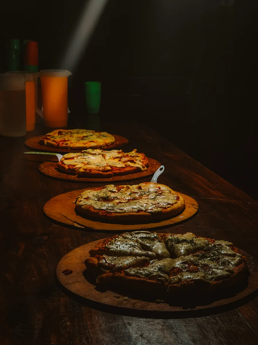 Pizzas caseras en fila sobre la mesa de madera del quincho