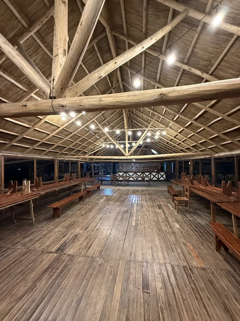 Un quincho por dentro, con mesas largas de madera y guirnaldas de luces en el techo
